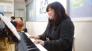 オレンジリングをつけてピアノを演奏する学生